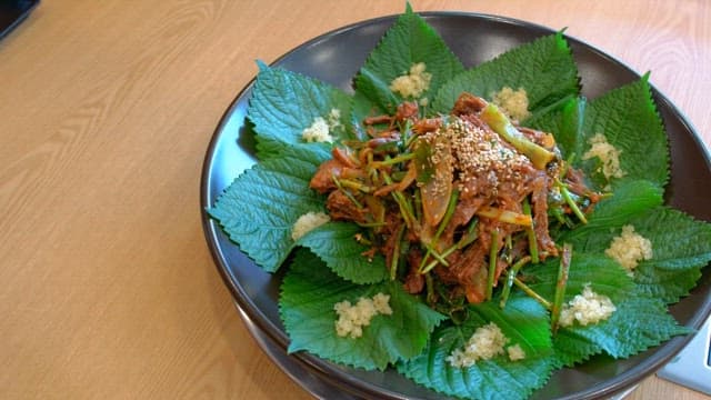 Spicy seasoned meat with perilla leaves on a plate on a wooden table