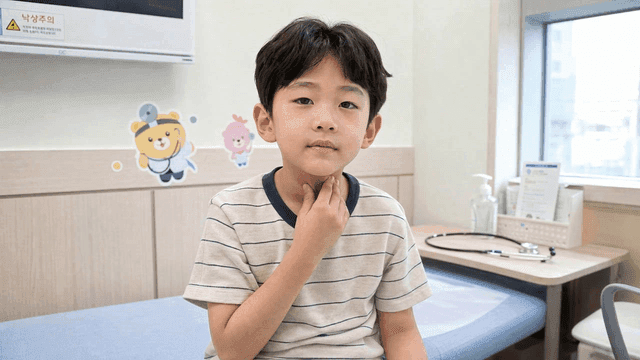 Male child patient touching his neck in examination room