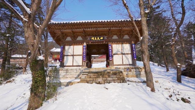 Snow-covered traditional Korean gateway in winter