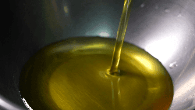 Oil being poured into a metal bowl