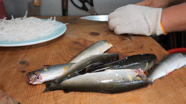 나무 도마 위에서 신선한 전어 손질하기