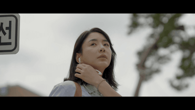 Woman smiling faintly as she takes out her earphones