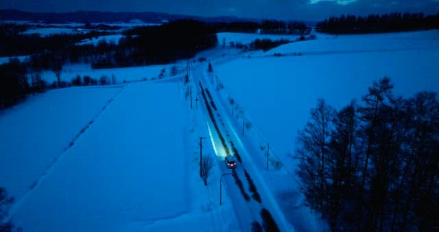 저녁의 눈 덮인 풍경을 지나가는 자동차