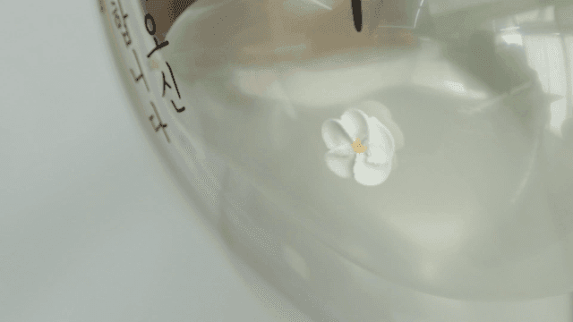 Fingers attaching small white flowers to balloon