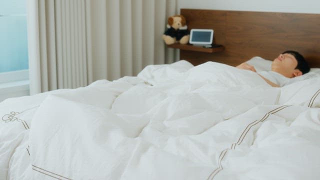 Man waking up and checking phone in bed