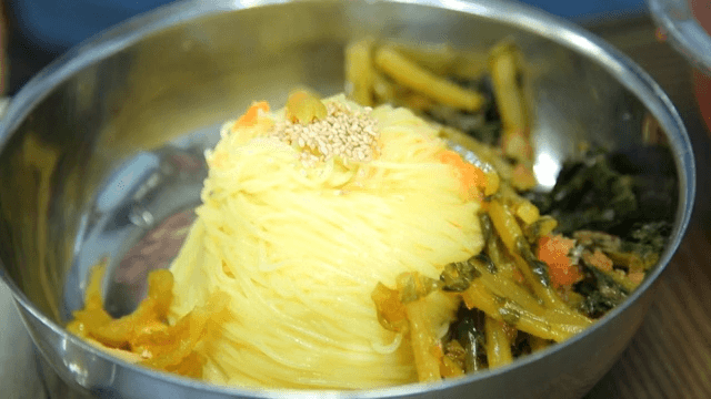 그릇에 담긴 차가운 국수에 열무김치를 넣는 장면