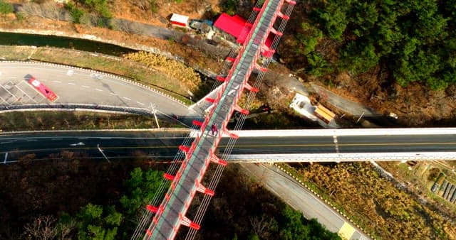 Aerial View of Red Suspension Bridge Over Road