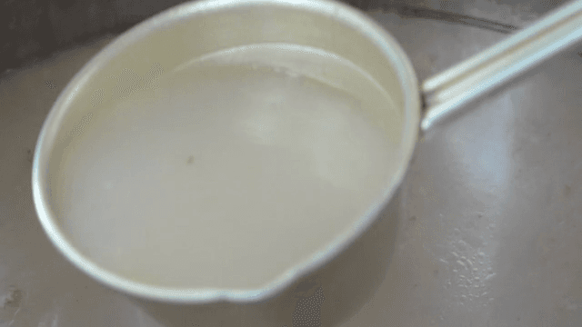 Ladle scooping broth from a large pot