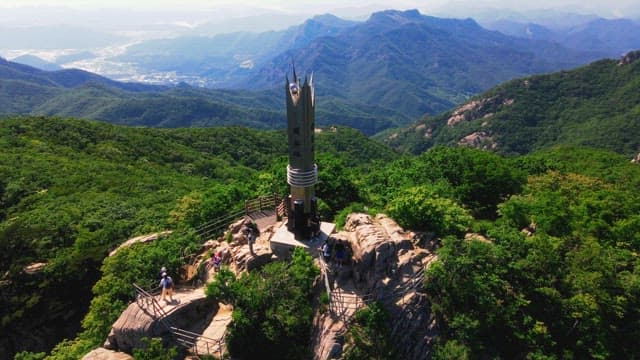 Tower located on the top of a mountain where hikers are present.