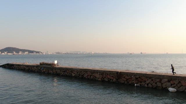 황혼의 평화로운 바다 방파제에서 조깅하는 사람