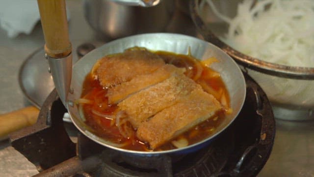 스토브 위에서 돈가스와 계란물로 가츠동을 만드는 모습