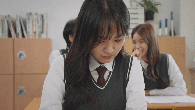 Boy and girl in the back laughing while a girl looks distressed