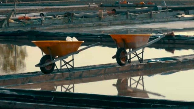 잔잔한 표면의 염전과 소금 수확 장비