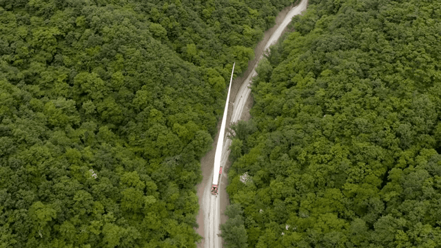 Transporting wind turbine materials on a road through a dense forest