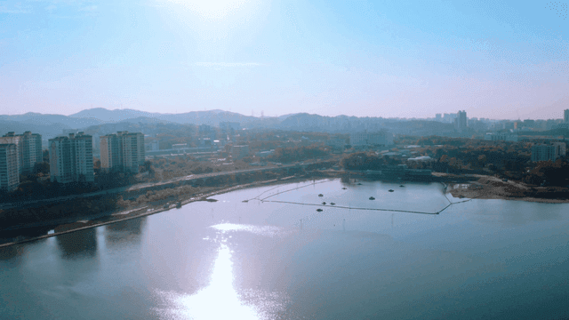 A city skyline with a river reflecting sunlight