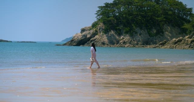 Woman Soaking Her Feet in Cool Sea Water on a Clear Day