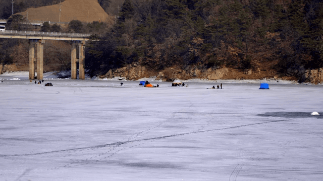 얼어붙은 호수에서 얼음 낚시하는 사람들