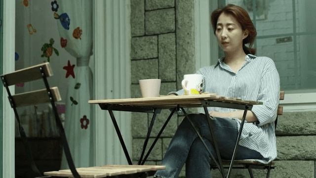 야외 테이블에서 생각이 잠긴 채 앉아있는 여성