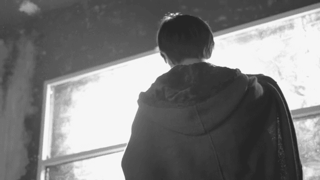 어두운 방에서 창밖을 바라보는 사람