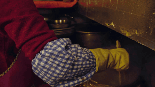 Person cooking with chopsticks in steamy kitchen