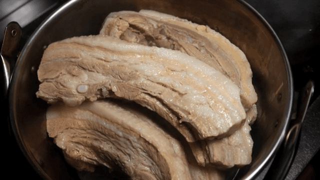 Boiled pork being transferred into a pot
