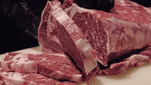 마블링이 있는 큰 소고기 덩어리를 자르는 모습