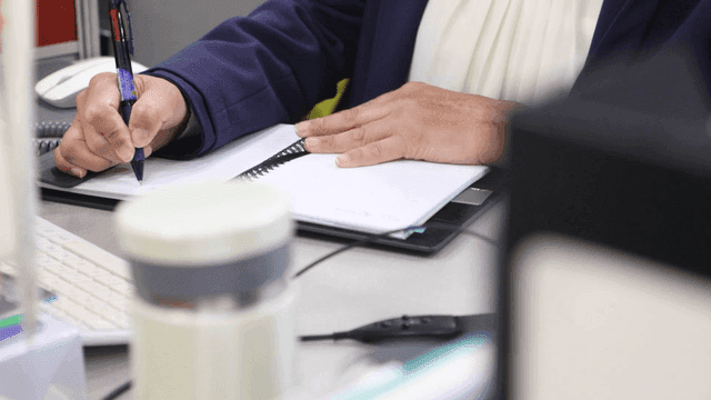 책상에서 메모를 하는 사람