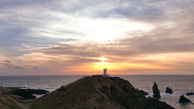 Lighthouse on a hill at sunset