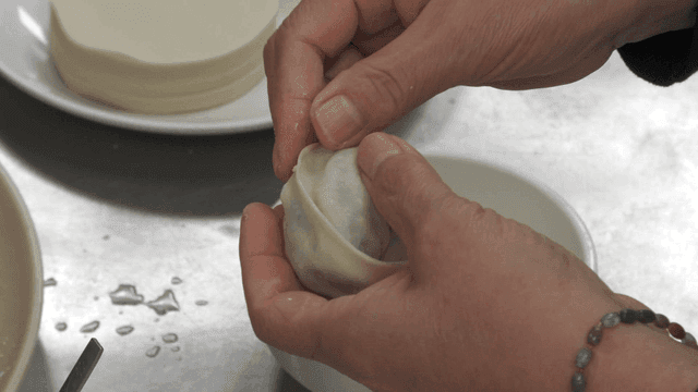 Hands making dumplings in a kitchen
