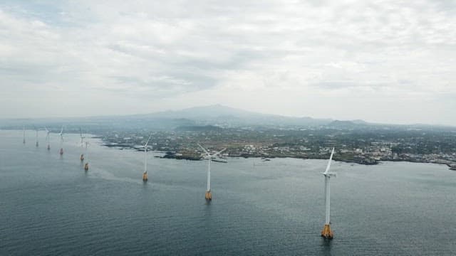 Wind turbines spinning on a calm sea on a cloudy day