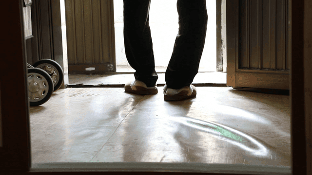 Elderly person entering a room wearing slippers