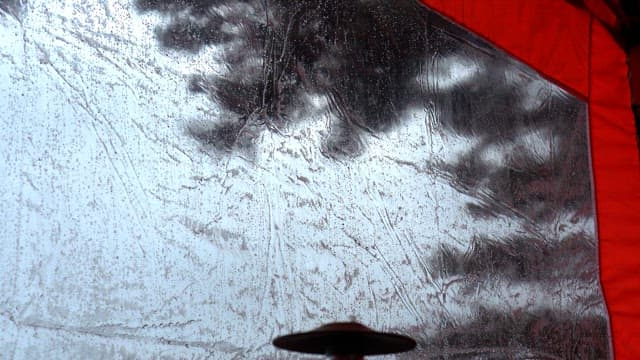 Raindrop-covered tent wall on a rainy day