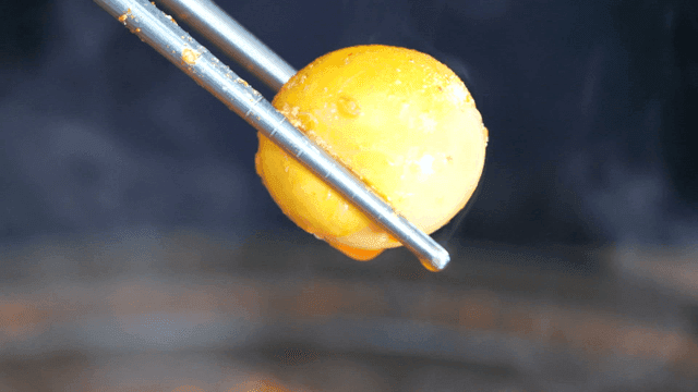 Chopsticks picking up egg in spicy chicken offal soup