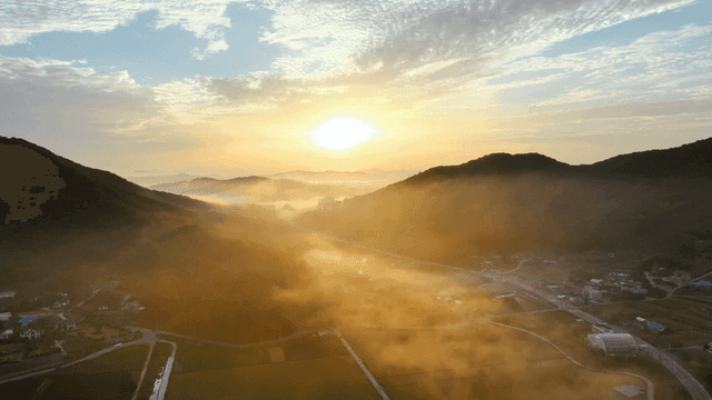 안개 낀 산과 들판 위의 일출