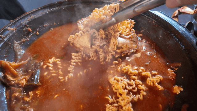 Sight of ramen boiling in spicy yellow crab stew