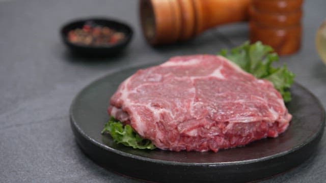 양념과 함께 검은 접시에 담긴 생 스테이크