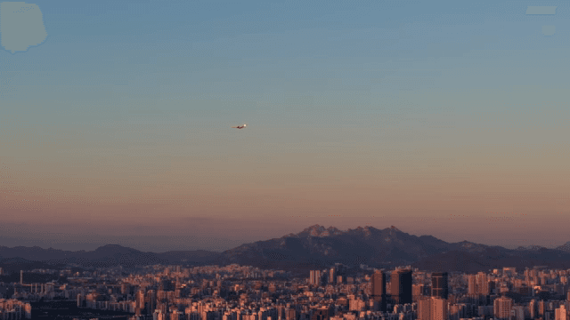 멀리 산이 보이는 도시 전경에 석양이 내려앉은 모습
