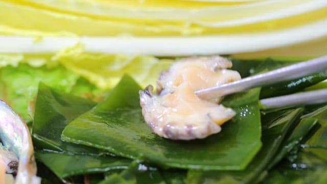 젓가락으로 집은 미역과 신선한 전복