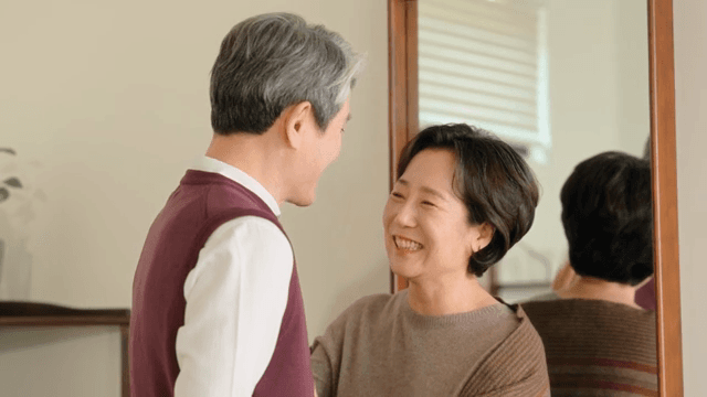 Elderly couple smiling while talking in front of a mirror