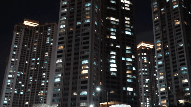 Stone statue in front of high-rise apartment building at night