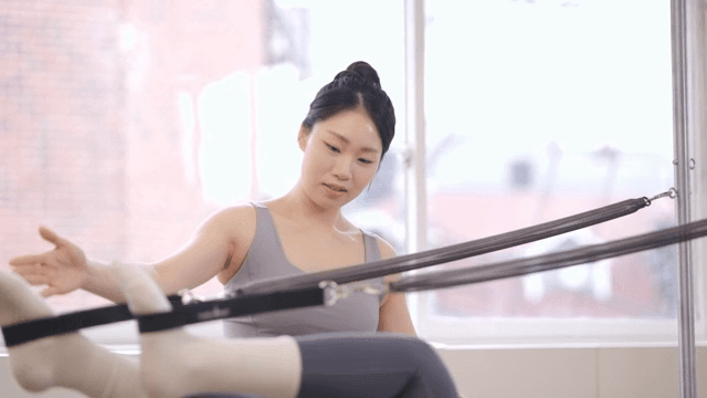 Pilates instructor assists a student indoors