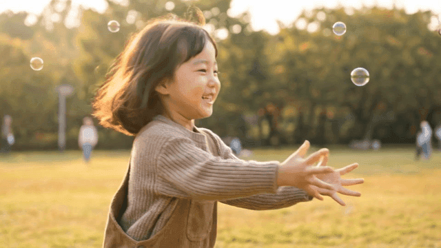Child playing with bubbles in park