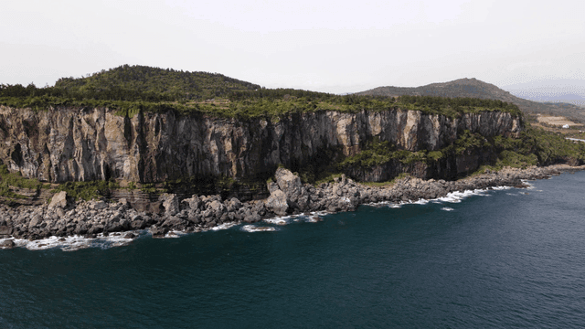 Scenery of coastal cliff with crashing waves.
