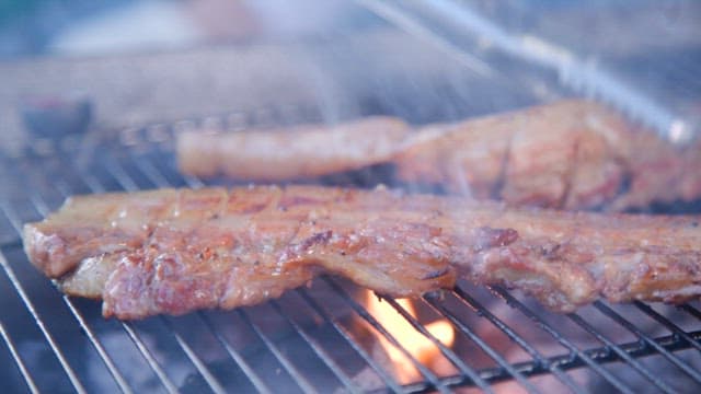 Delicious marinated pork ribs grilled on a barbecue grill with flames