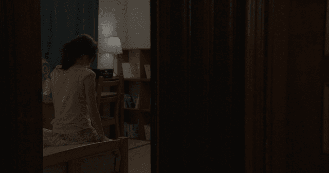 어두운 방에서 침대에 앉아 있는 소녀
