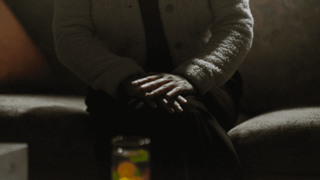 Middle-aged woman sitting on sofa in dark living room