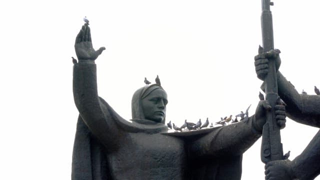 도시의 큰 동상 위에 앉은 비둘기들