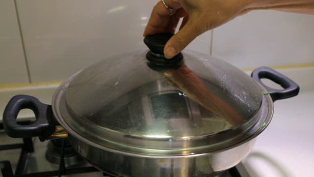 스토브 위 냄비에서 요리되는 초록색 채소찜