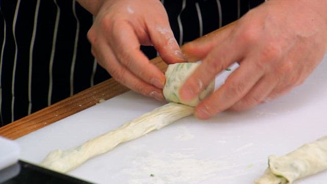 Hands shaping flour dough with green onion