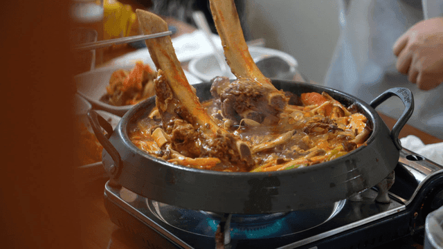 People eating braised beef short ribs boiling in pot